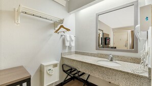 Un baño moderno con encimera de granito, un espejo grande, un perchero y un secador de pelo.