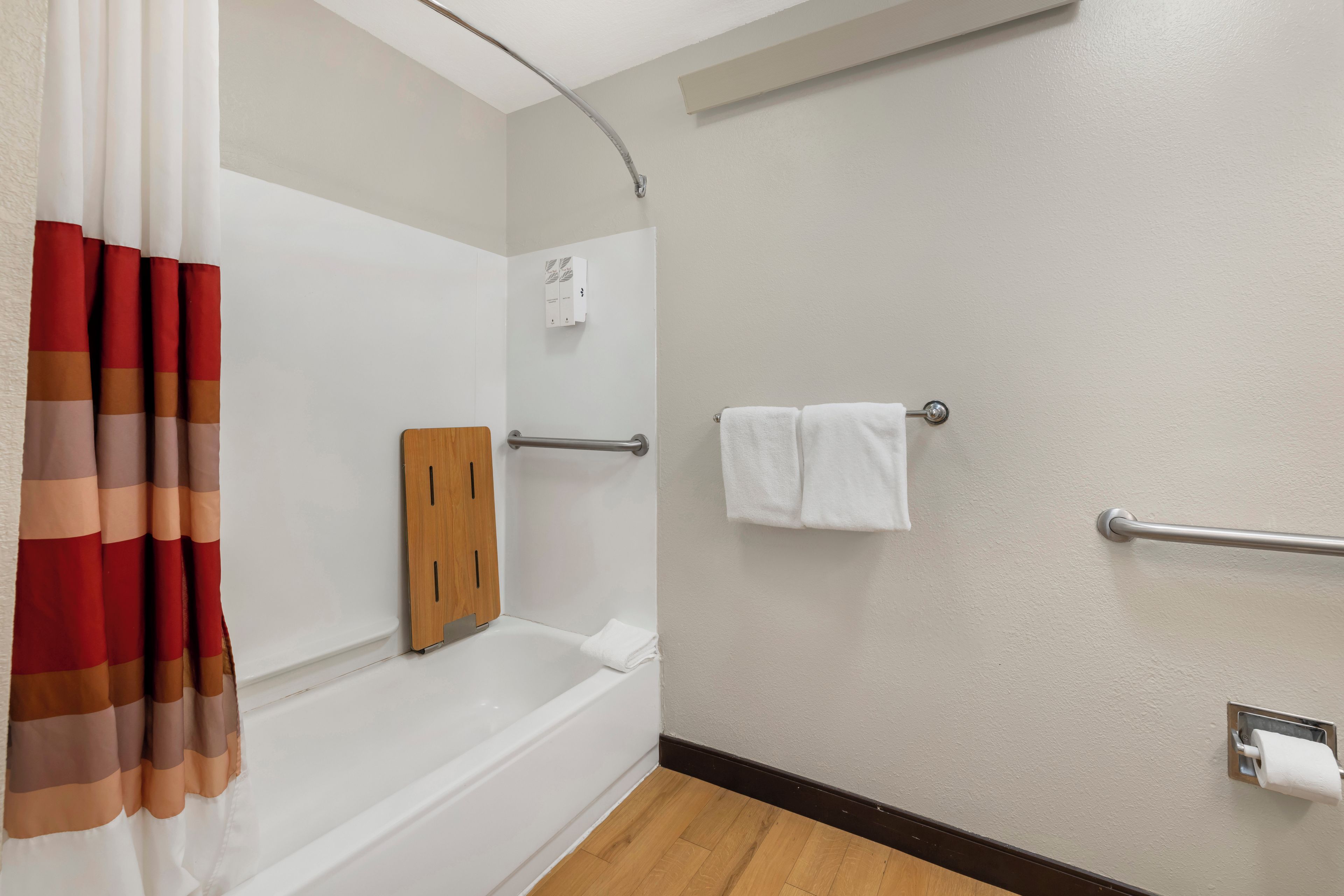Une salle de bain équipée d’une baignoire, d’une douche, d’un porte-serviettes et d’un support à papier toilette.