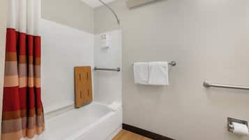 Une salle de bain équipée d’une baignoire, d’une douche, d’un porte-serviettes et d’un support à papier toilette.