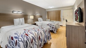 Habitación de hotel con dos camas, televisión, escritorio y ventana con cortinas.