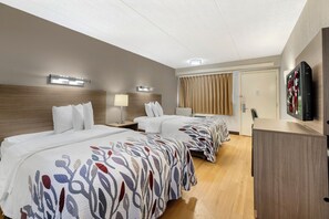 Quarto de hotel com duas camas, televisão, escrivaninha e janela com cortinas.