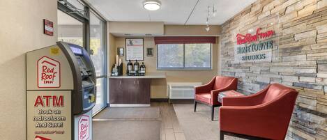 An indoor area with an ATM, a reception desk, and a seating area with chairs.