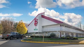 A Red Roof Inn with a white exterior and a red roof, located next to a road with a parked truck.