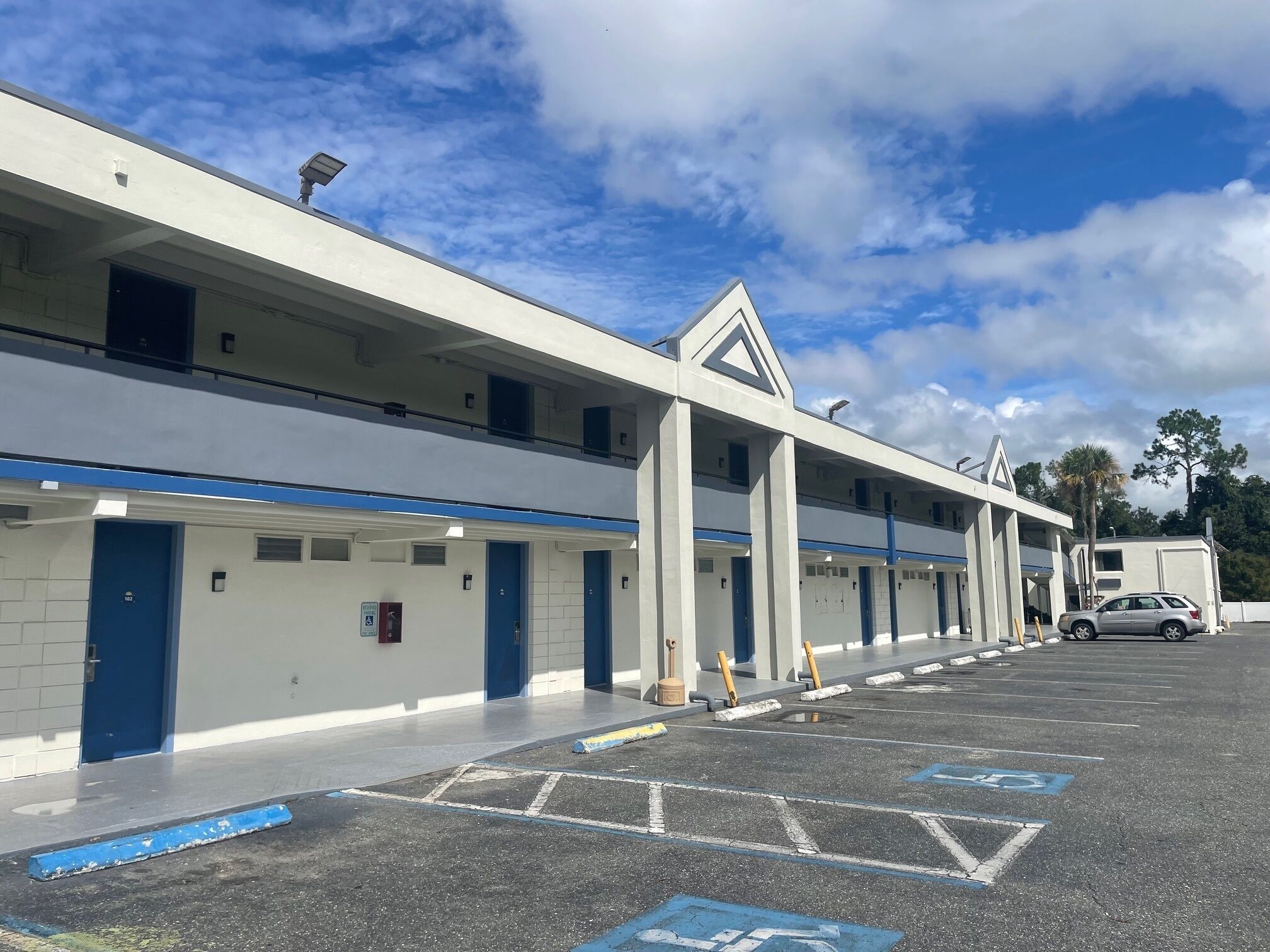 A multi-story parking garage with blue and white color scheme, multiple levels, and a car parked in the lot.