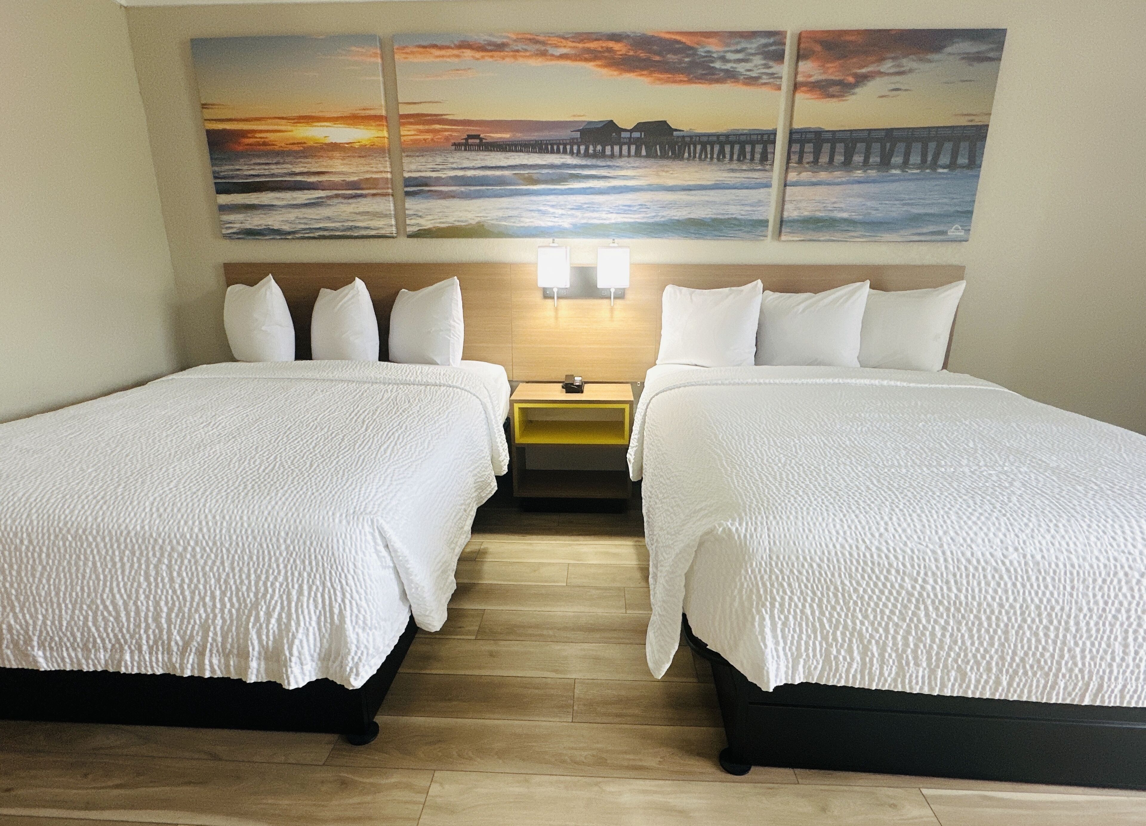Ein Hotelzimmer mit zwei Betten, einem Nachttisch und einer Wandlampe.