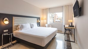 Una habitación de hotel con una cama grande, un escritorio y un televisor.