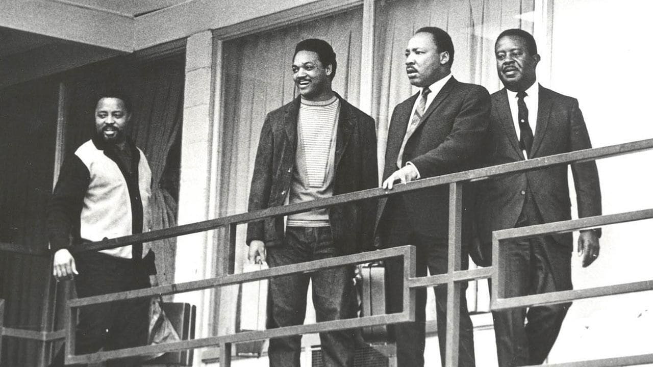 Un groupe d’hommes se tient sur un balcon doté de rampes en métal.