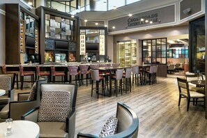 A modern bar area with a variety of seating options, including bar stools and tables, and a large television screen.