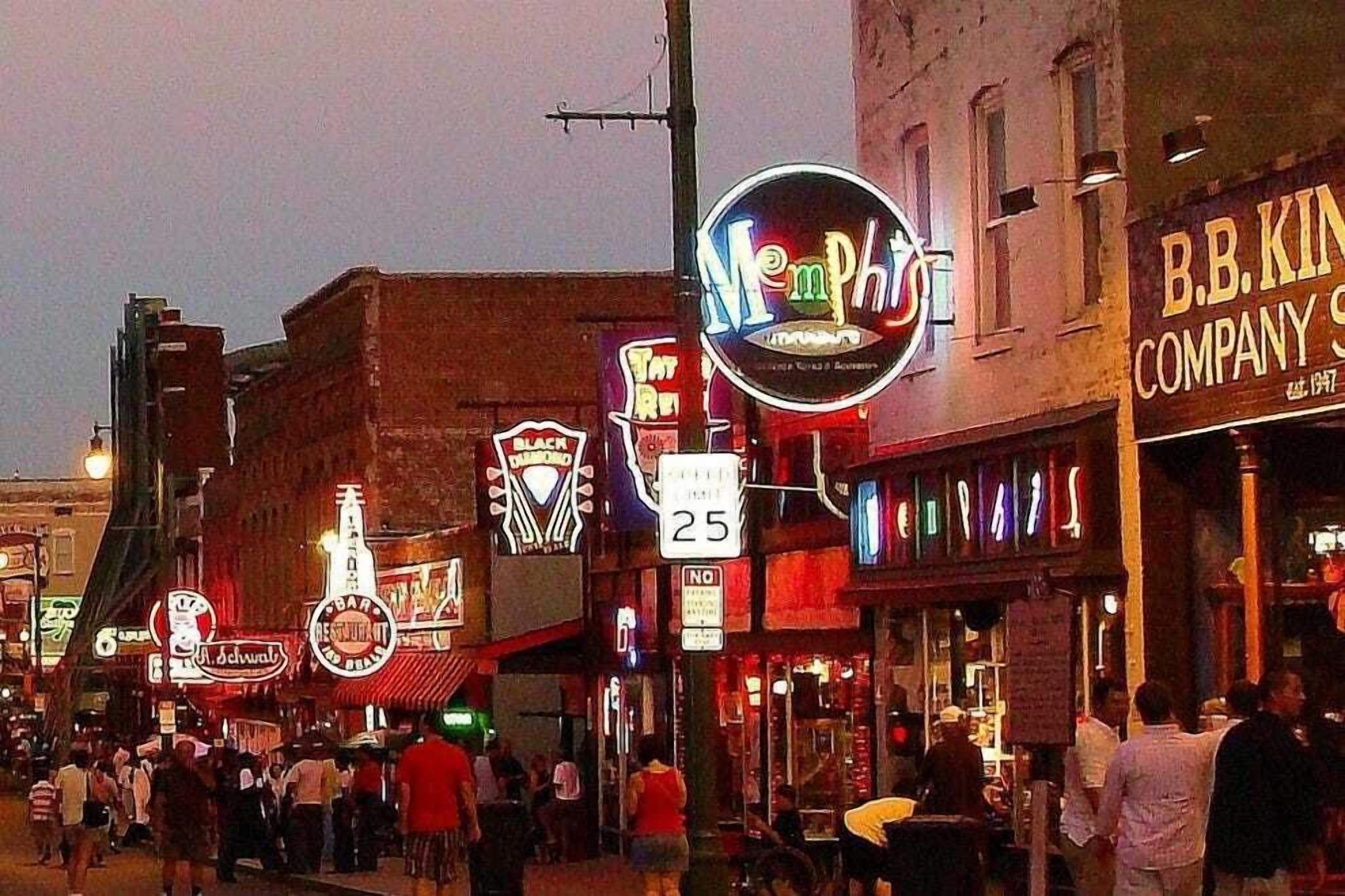 A busy street with various shops and signs, including a neon sign for 'Memphis' and a 'B.B. King' restaurant.