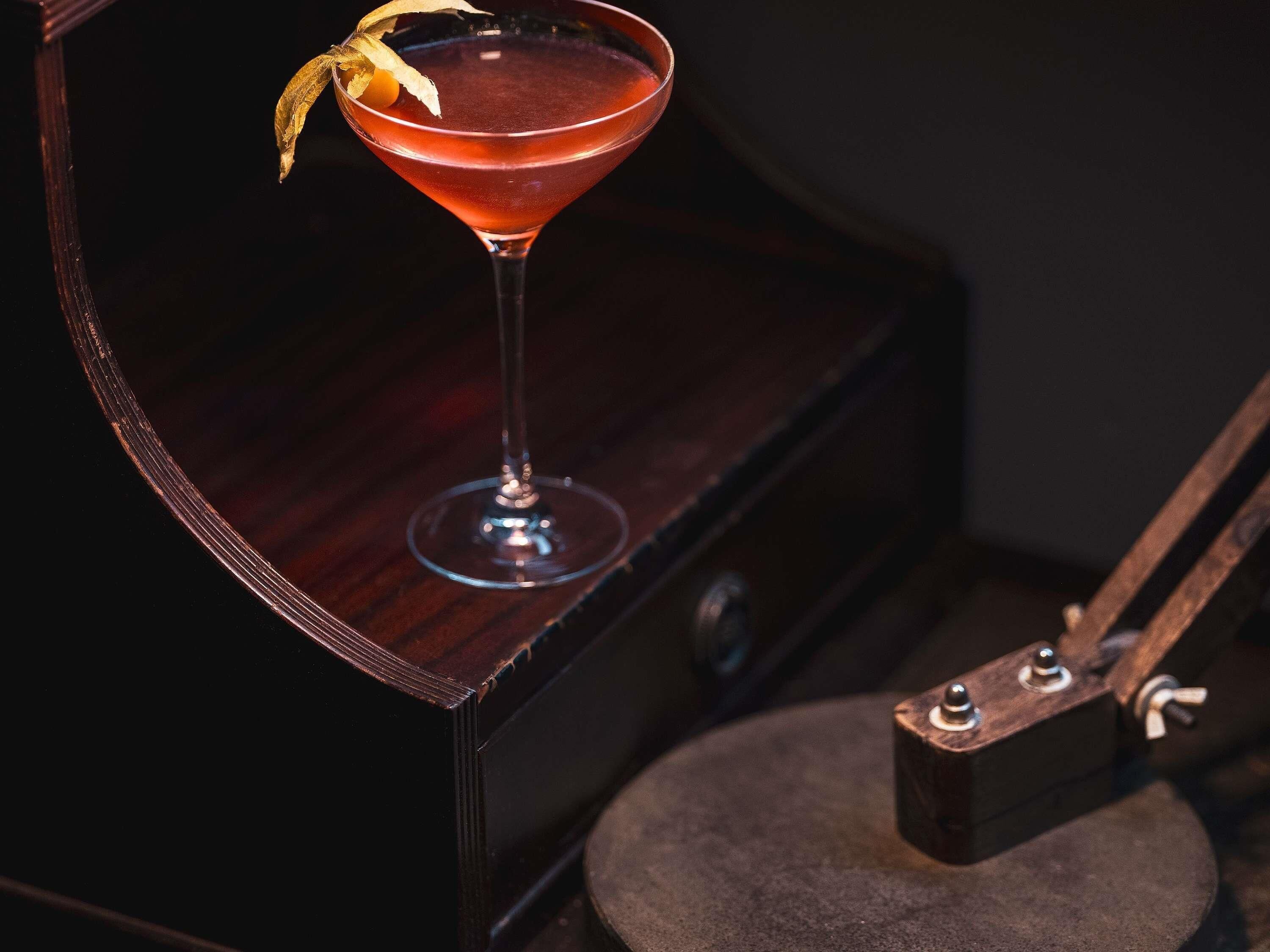 Un cóctel en una copa de martini sobre una superficie de madera.