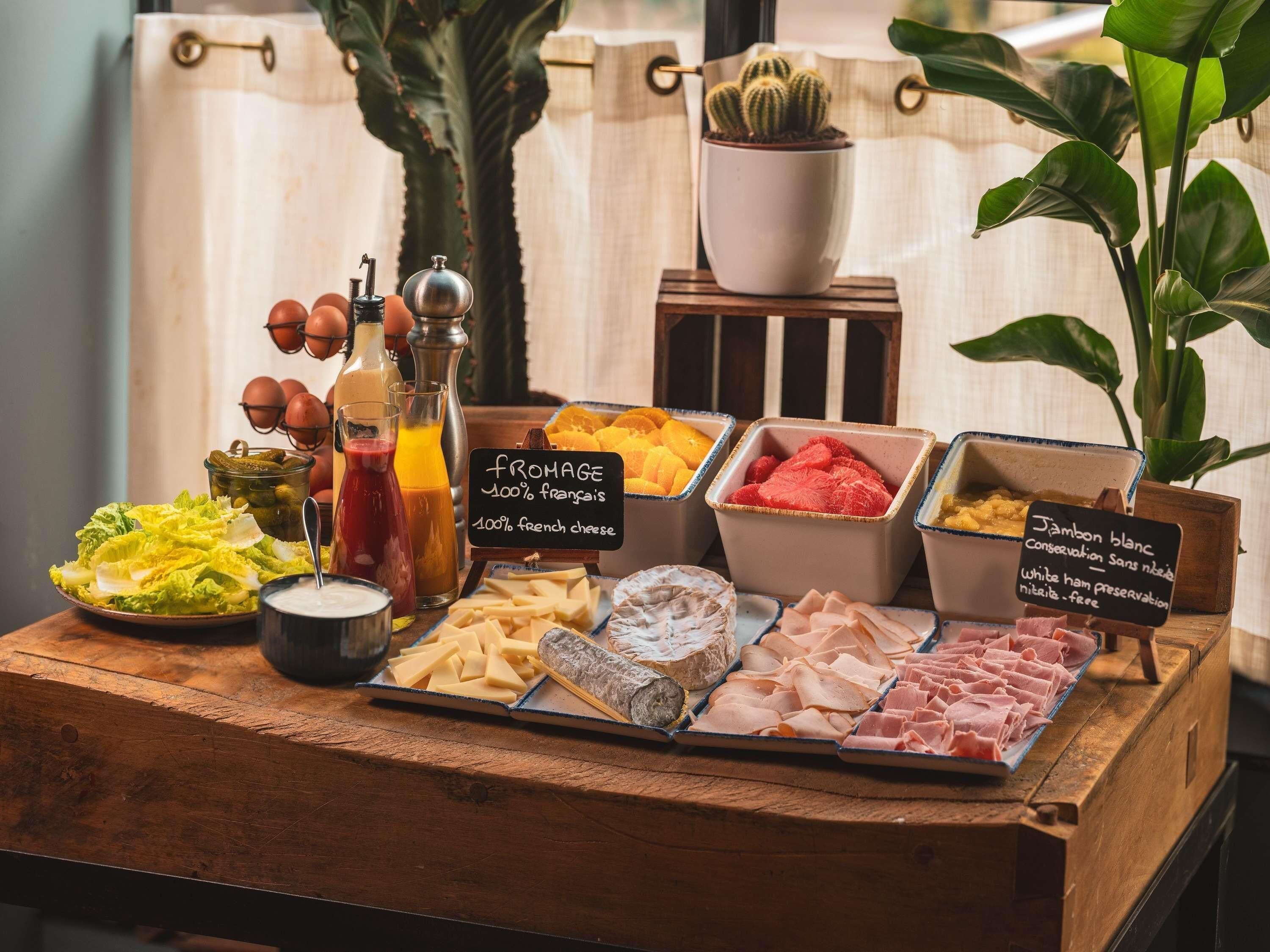 Una exhibición de alimentos con varios quesos, embutidos y frutas.