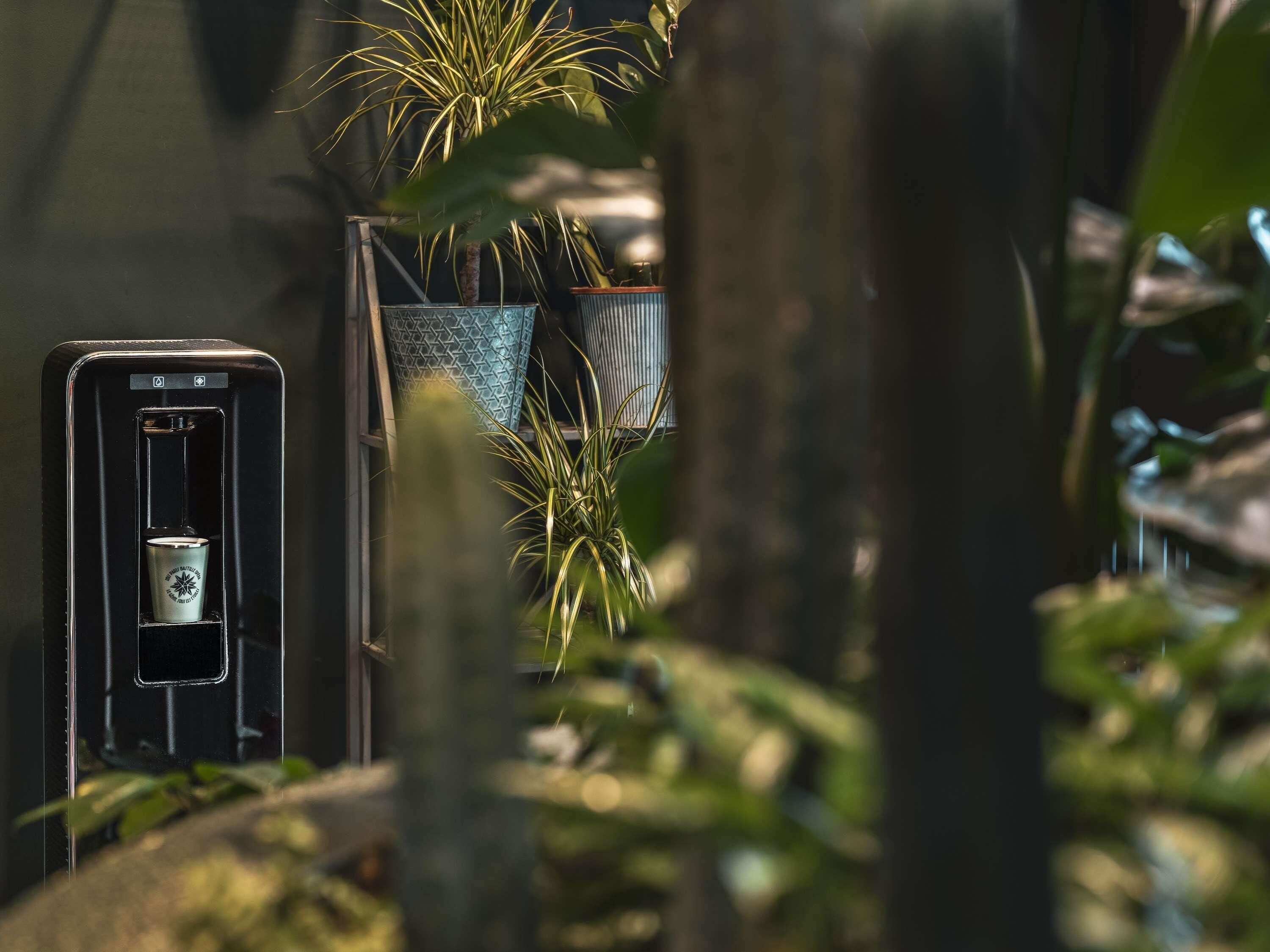 A smartphone with a cup in a holder, surrounded by plants.