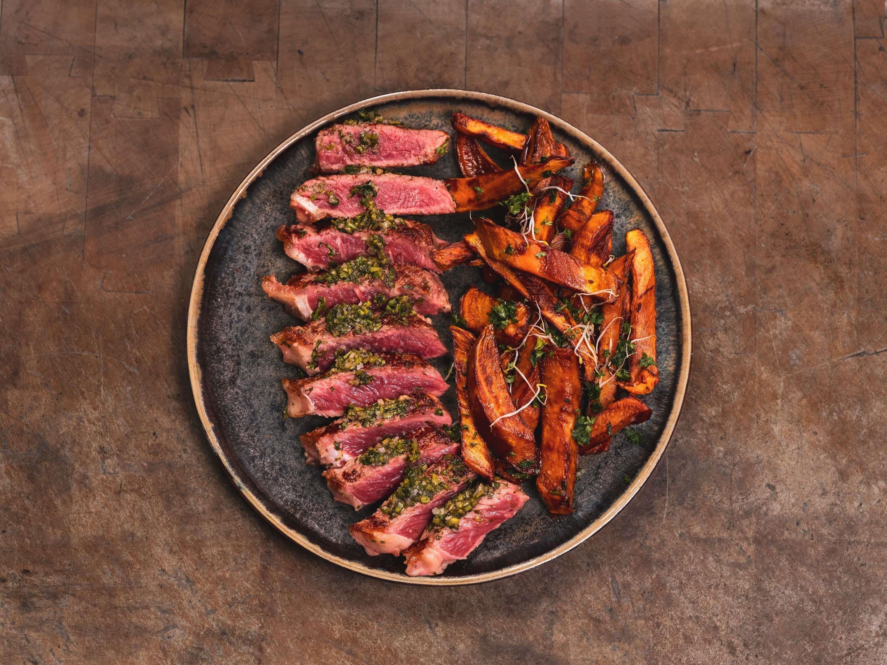 A plate of food with steak and roasted potatoes.