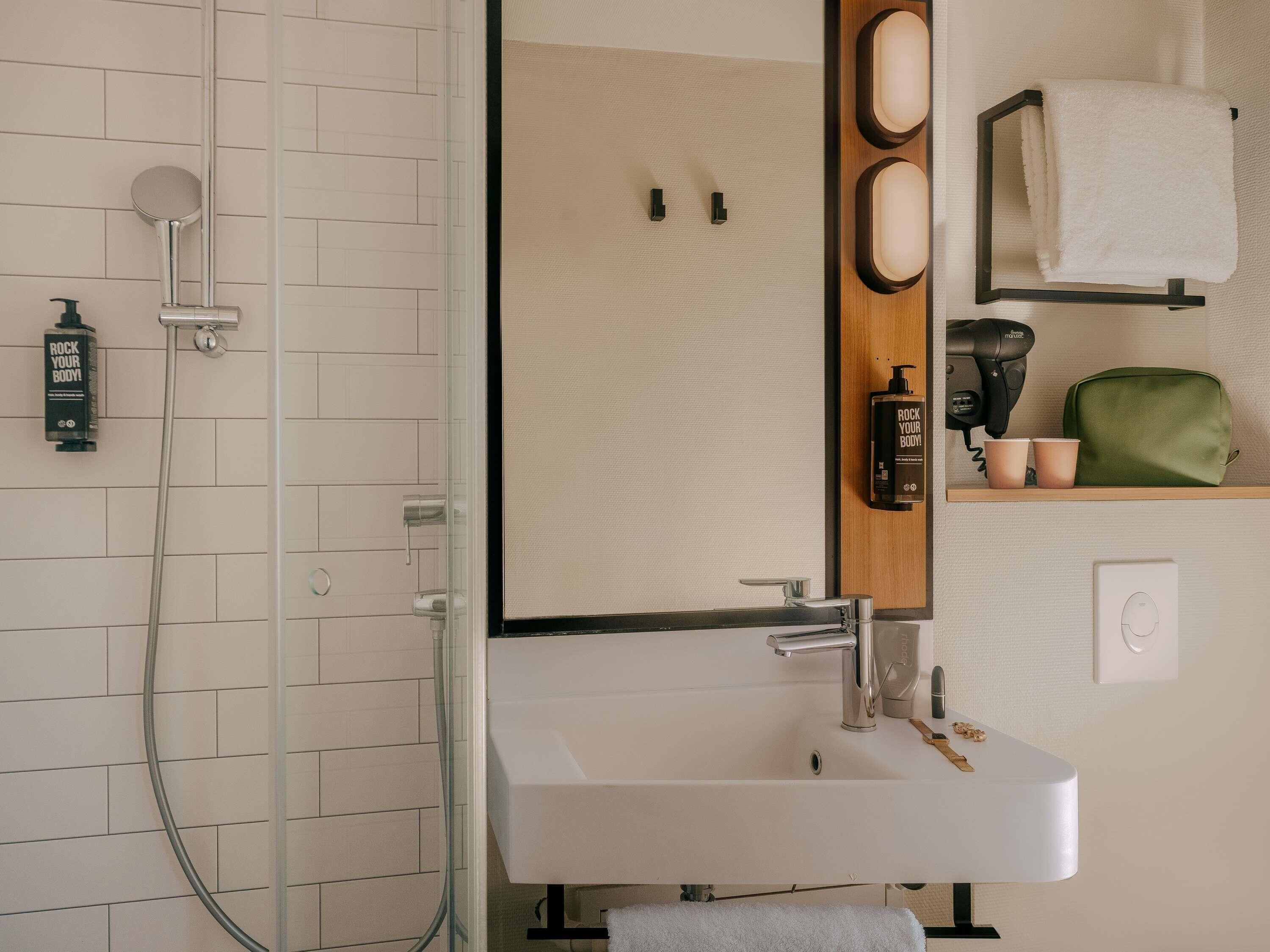 Ein modernes Badezimmer mit Dusche, Waschbecken und Handtuchhalter.