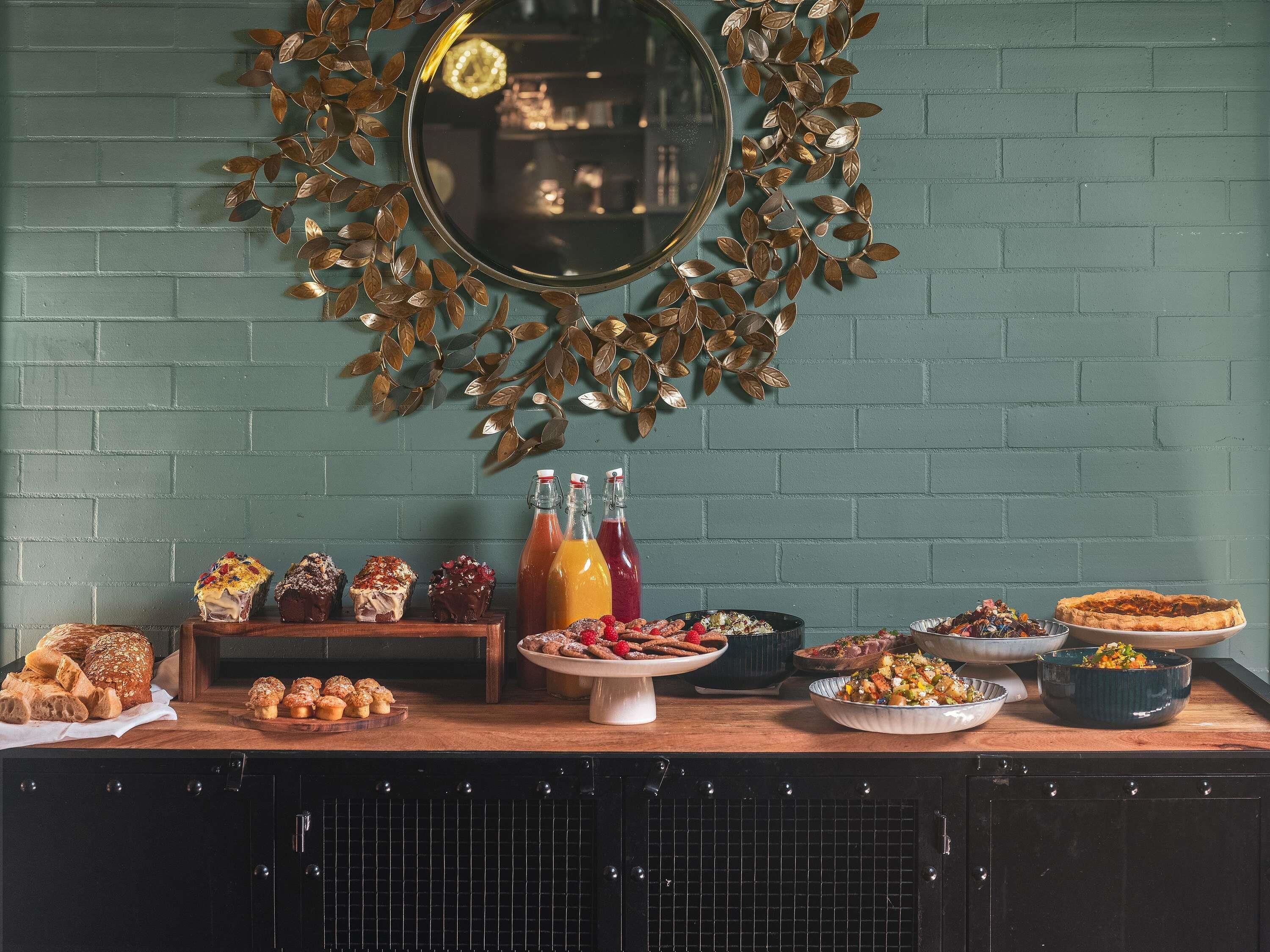 A kitchen counter with various baked goods, beverages, and a decorative mirror.