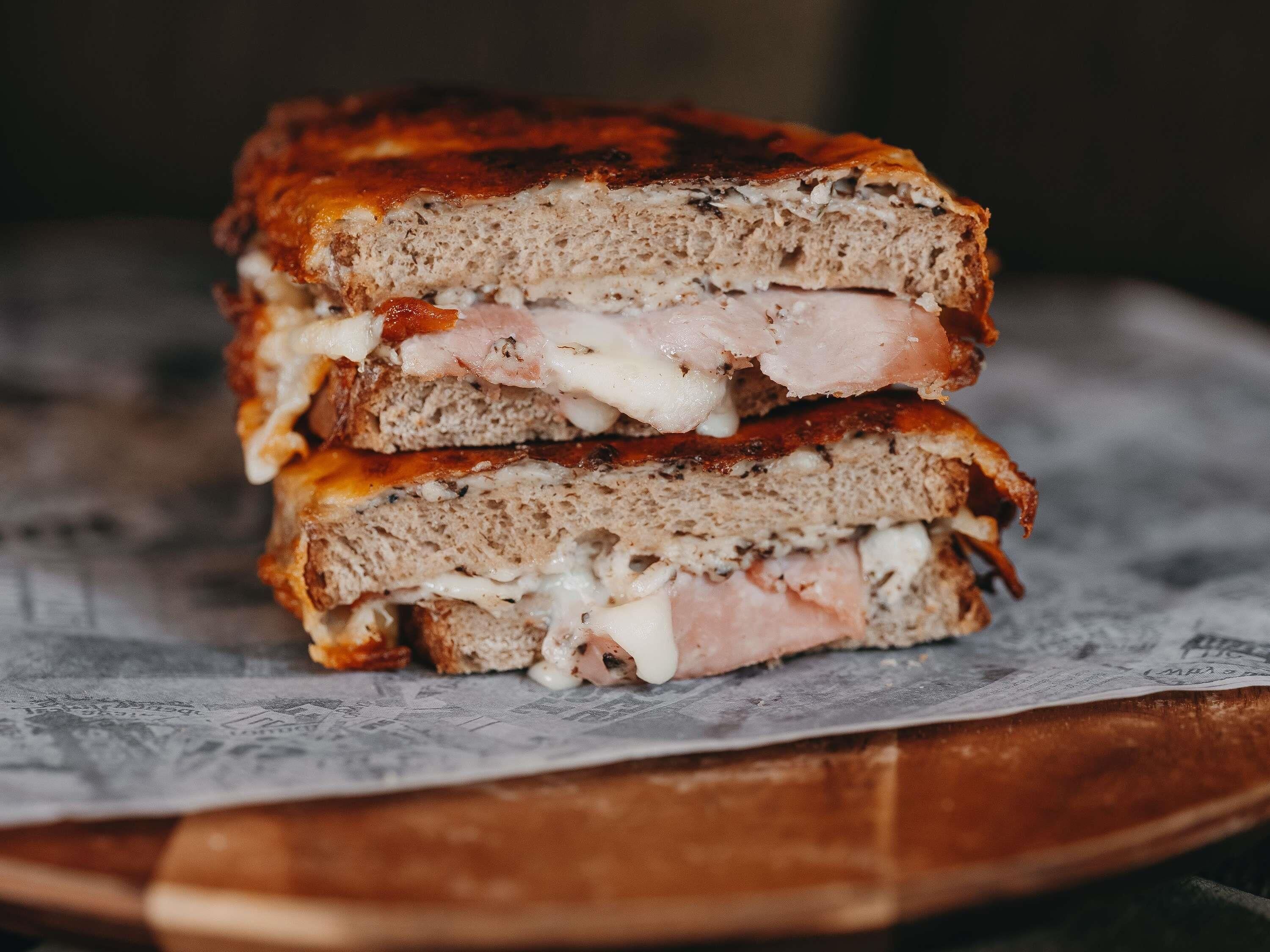 A sandwich with visible layers of bread, cheese, and meat.