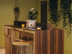 A reception desk with a laptop, a glass of orange juice, a plate of food, and a plant.