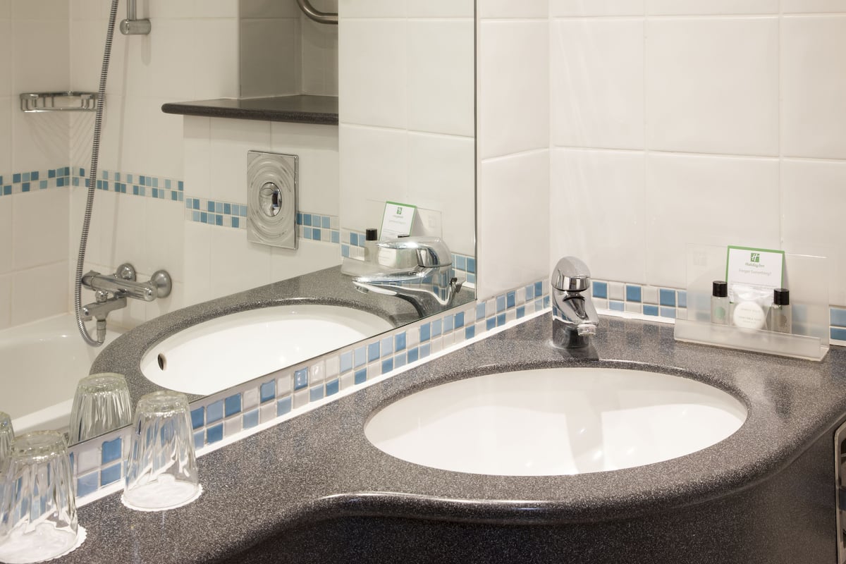 A bathroom with two sinks, a shower, and a mirror.