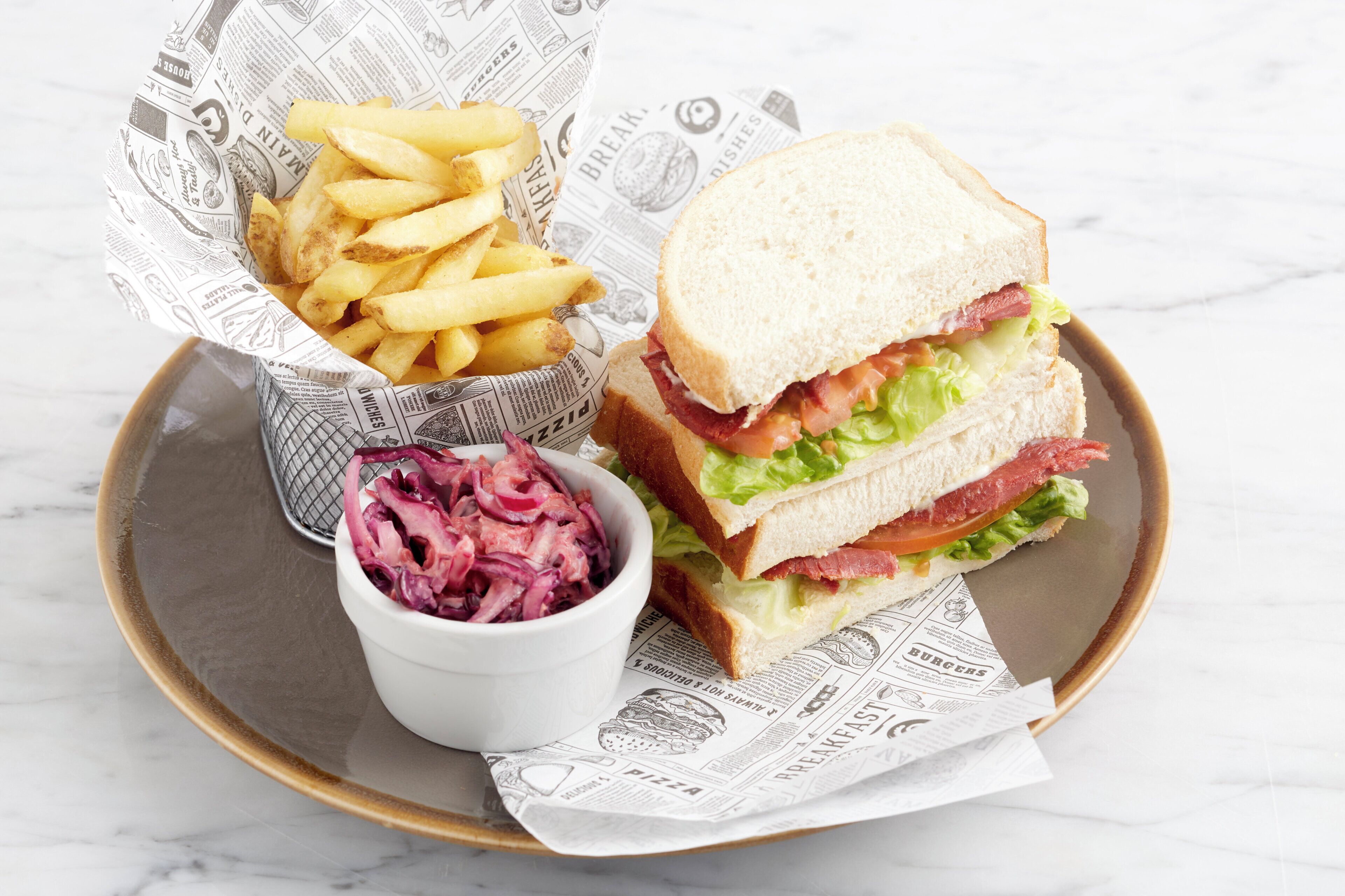A tray with a sandwich, French fries, and sauerkraut.