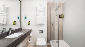 A modern bathroom with a large mirror, a sink, a toilet, and a glass-enclosed shower area. - Holiday Inn Ipswich by IHG (Ipswich)