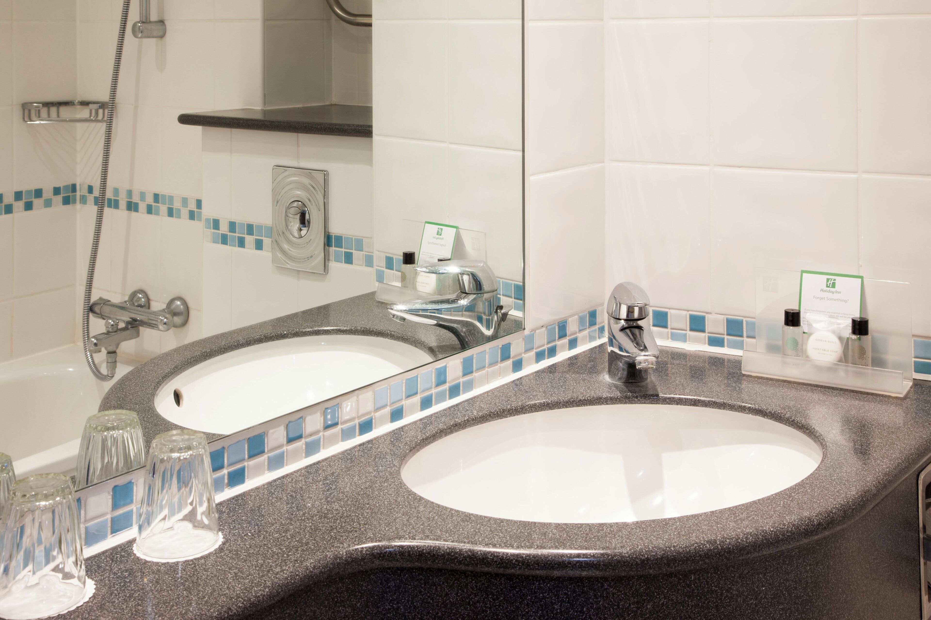 A bathroom with two sinks, a shower, and a mirror.