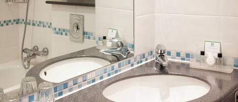 A bathroom with two sinks, a shower, and a mirror.