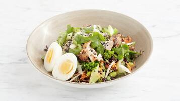 A bowl of salad with various vegetables and a boiled egg.