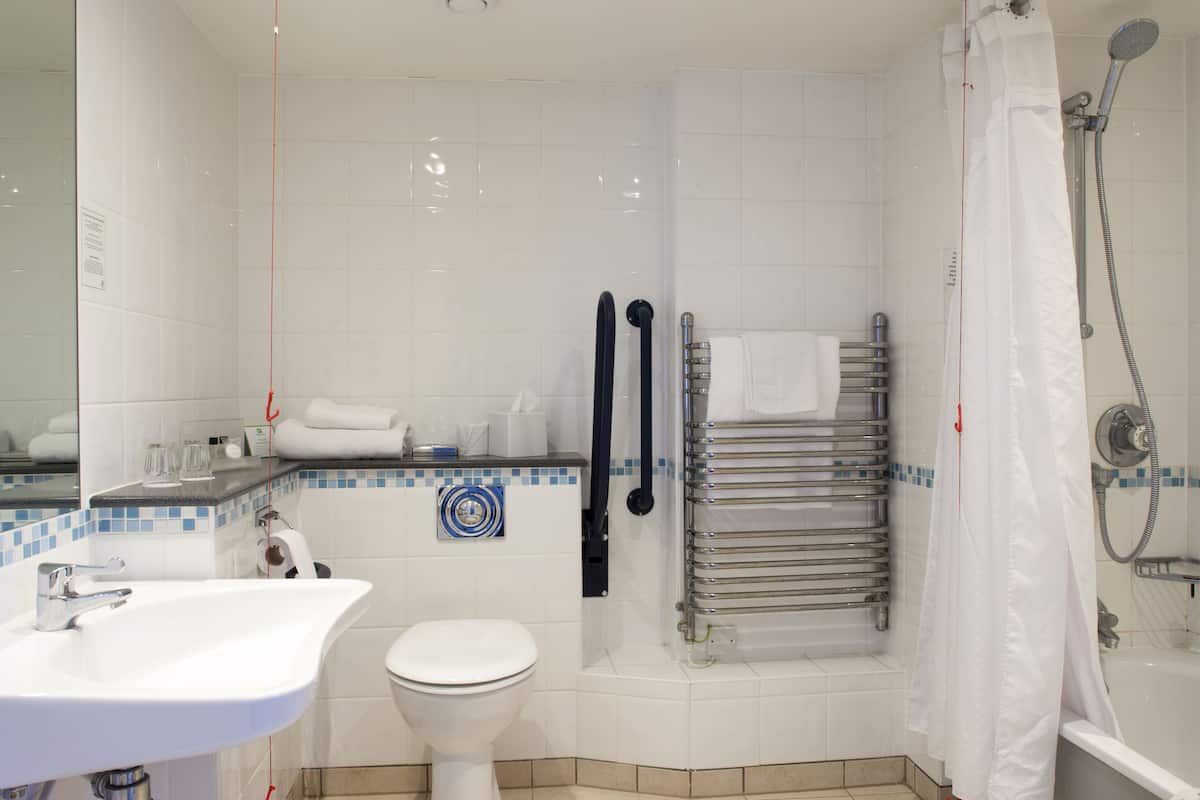 A bathroom with a sink, toilet, shower, and a towel rack.