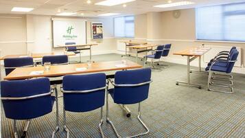 A conference room with tables, chairs, and a presentation screen.