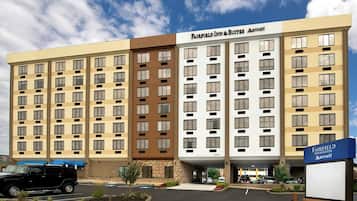A multi-story Fairfield Inn & Suites Marriott hotel with a parking lot and a clear sky.