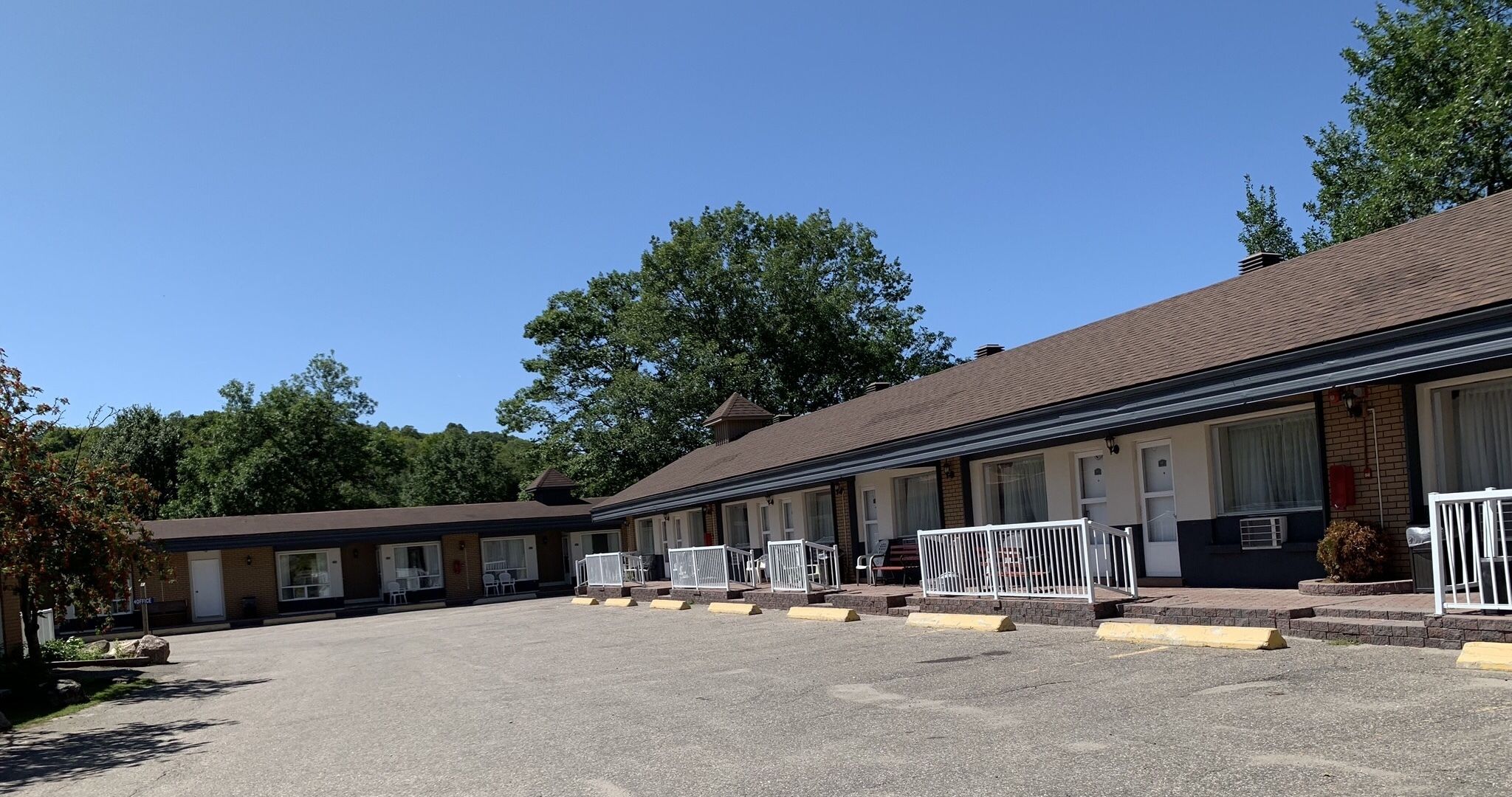 Un motel con varias habitaciones, un estacionamiento y un pequeño jardín.