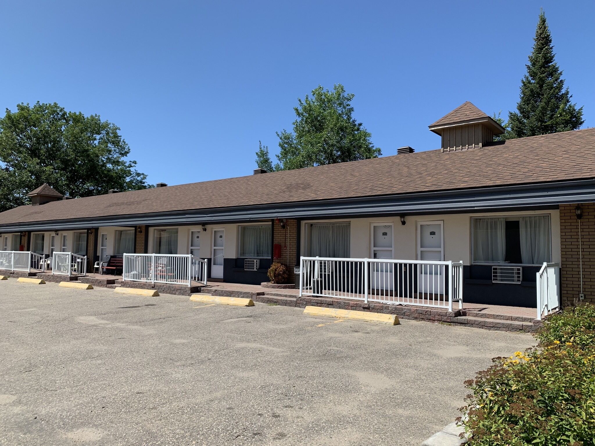 A motel with multiple rooms, each with a balcony and a small porch area.