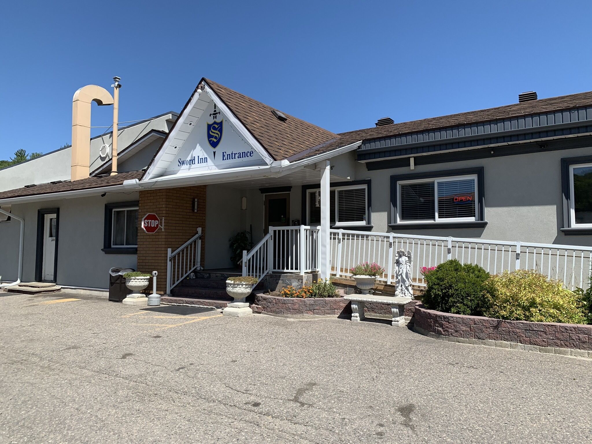 A building with a sign reading "Sword Inn Entrance" and a stop sign nearby.