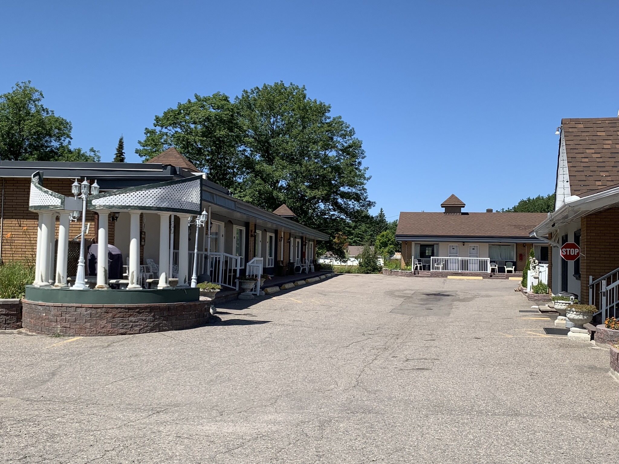 A building with a covered porch, a stop sign, and a gravel driveway.
