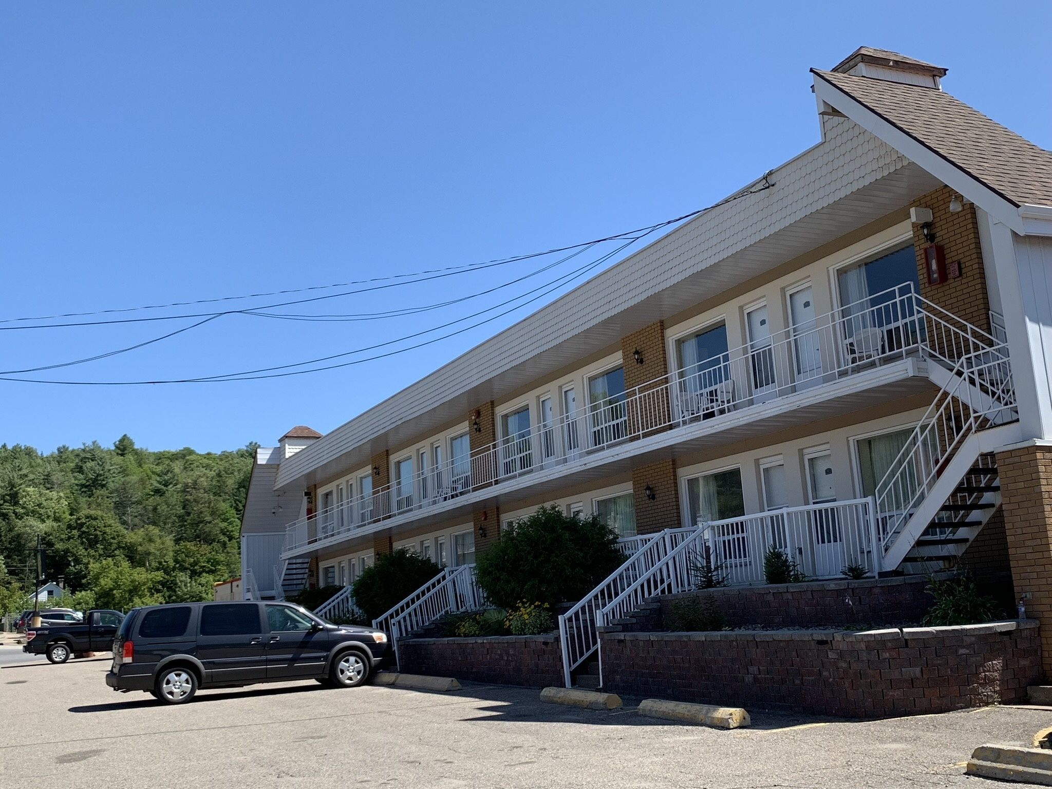 A multi-story motel with a brick facade, white railings, and a parking lot.