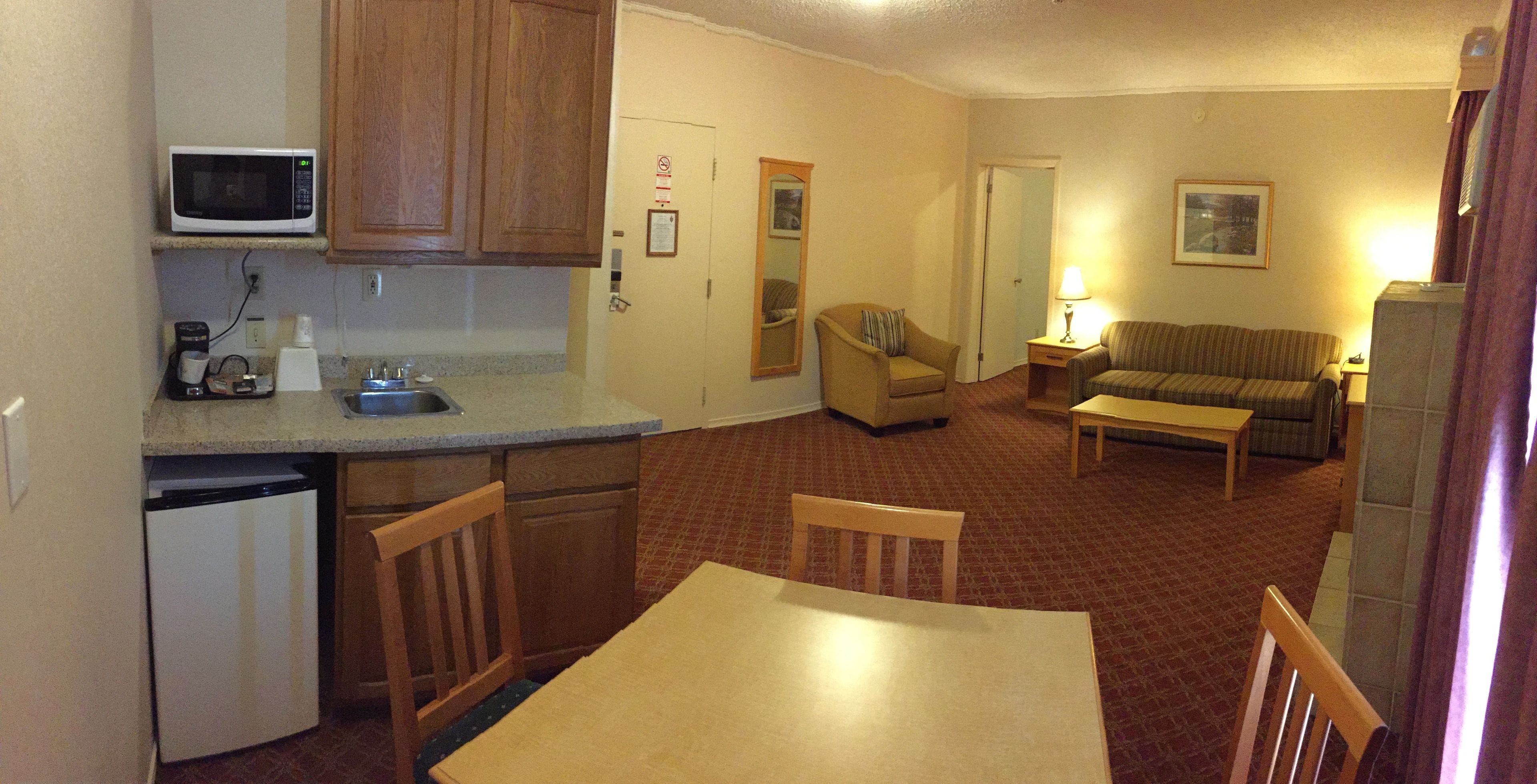 A compact living space with a kitchenette, a dining area, and a seating area with a sofa and a chair.