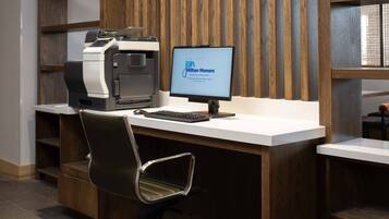 Uma mesa de recepção com um monitor de computador exibindo 'junte-se ao Hilton Honors' e uma impressora.