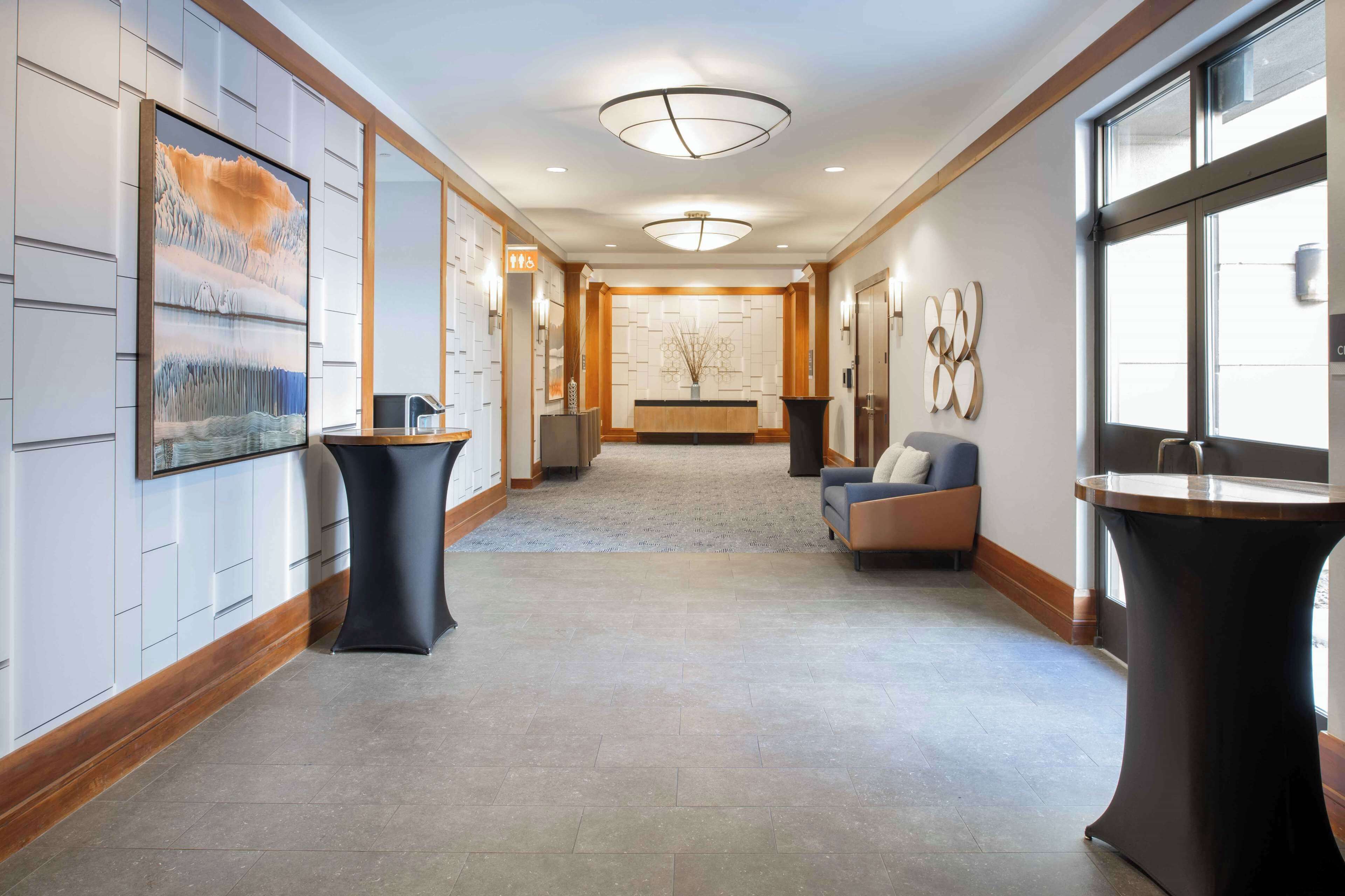 A hotel lobby with a reception desk, seating area, and artwork on the walls.