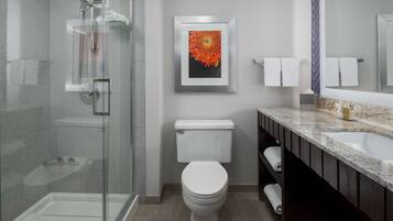 Une salle de bain moderne avec une douche à parois de verre, des toilettes, un lavabo et une œuvre d’art encadrée accrochée au mur.