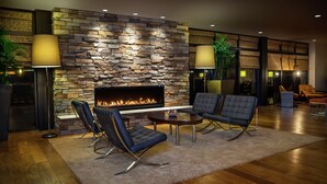 A modern living room with a stone wall fireplace, leather chairs, and a wooden floor.