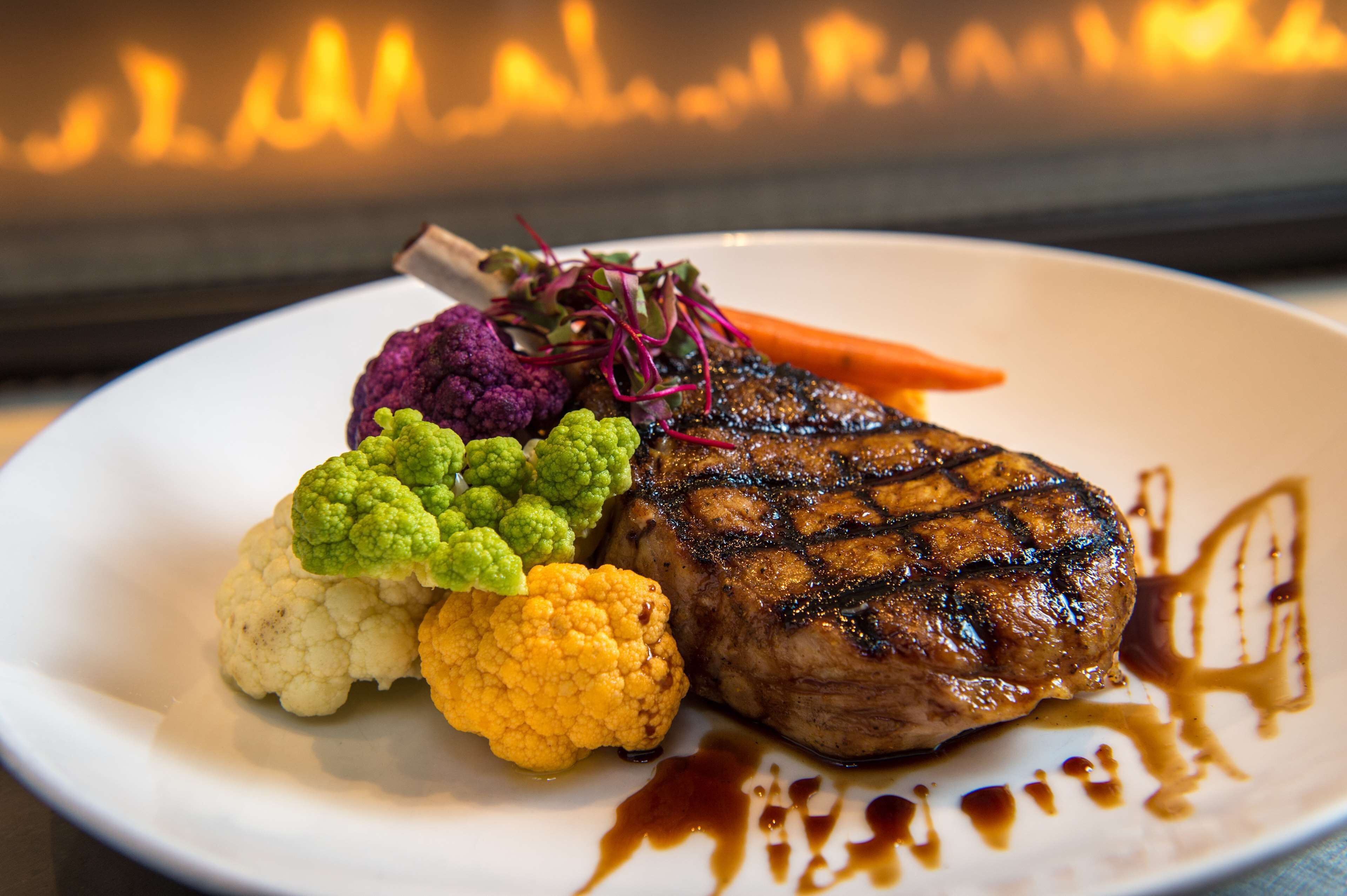A plate of food with a steak, cauliflower, and purple vegetables.