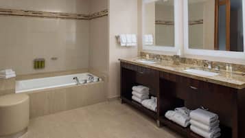 Un baño moderno con bañera, dos lavamanos y un espejo grande.