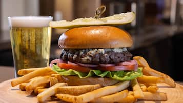 A burger with fries and a glass of beer on a wooden table.