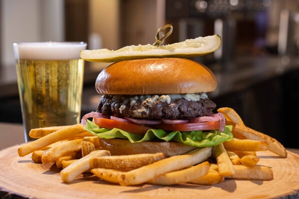 Una hamburguesa con papas fritas y una jarra de cerveza sobre una mesa de madera.