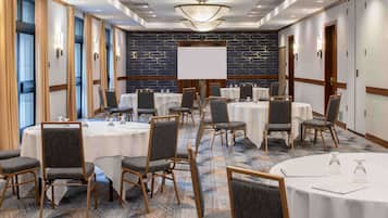Un salón de conferencias con mesas redondas, sillas y una pizarra grande.
