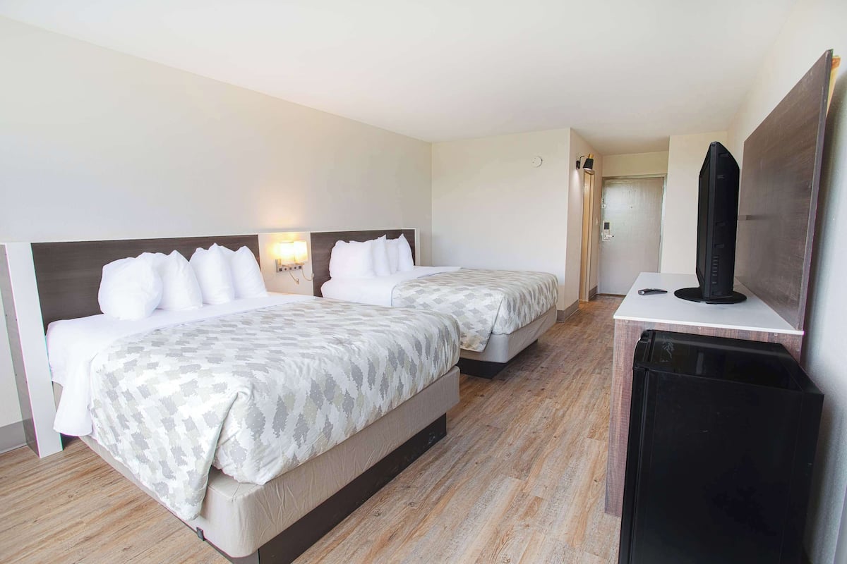 A hotel room with two beds, a TV, and a small table.
