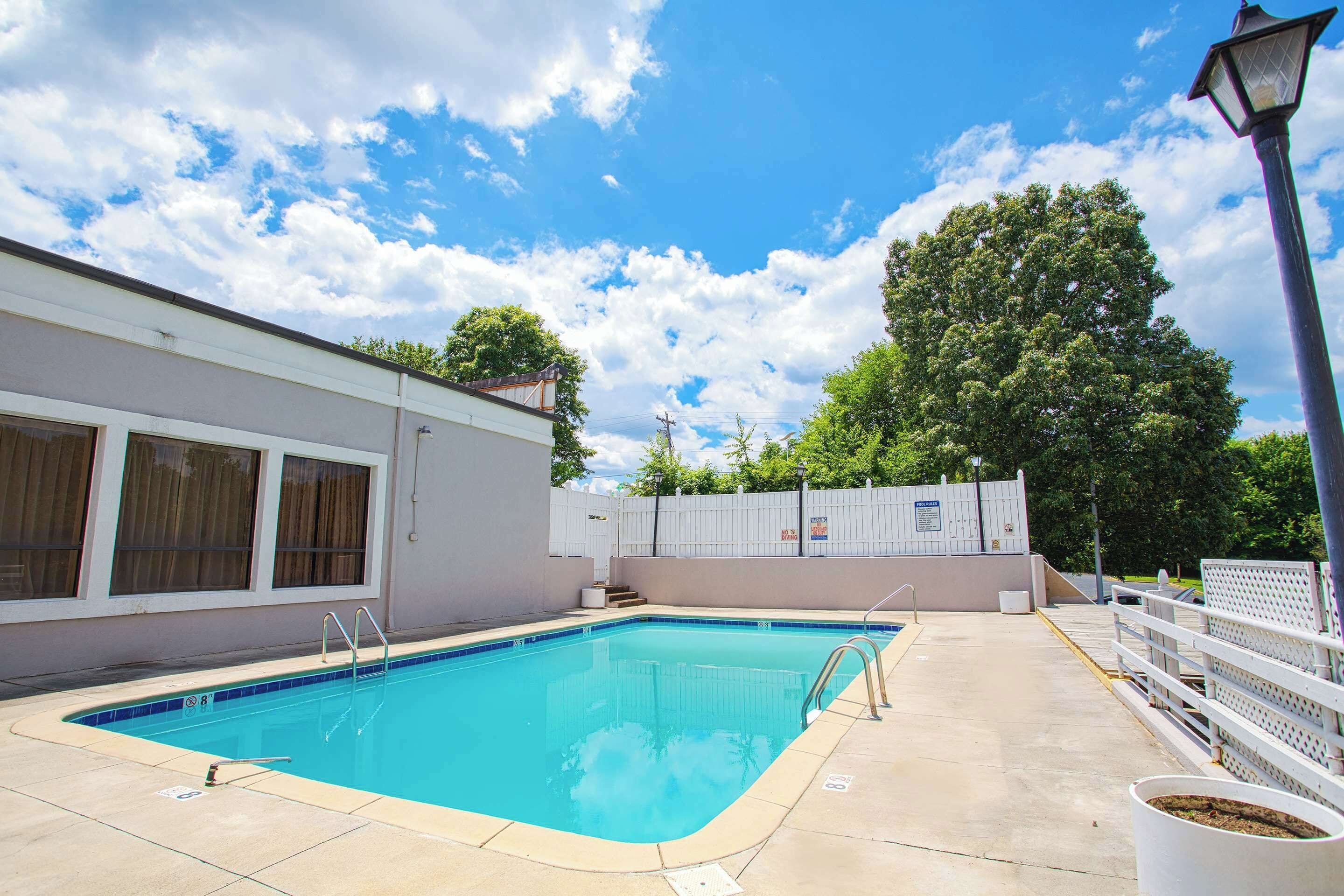 Una piscina con cerco blanco, un farol y un edificio con ventanas.
