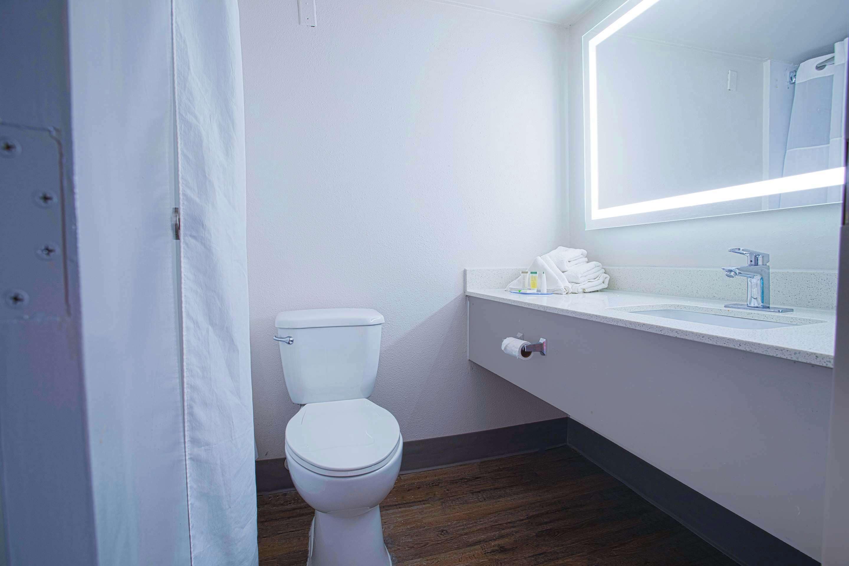 Un baño moderno con inodoro, lavabo y espejo.