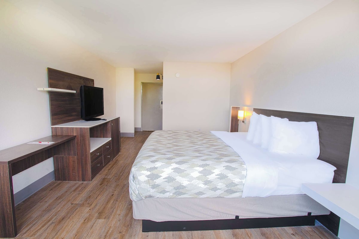 A hotel room with a bed, a desk, a television, and a nightstand.