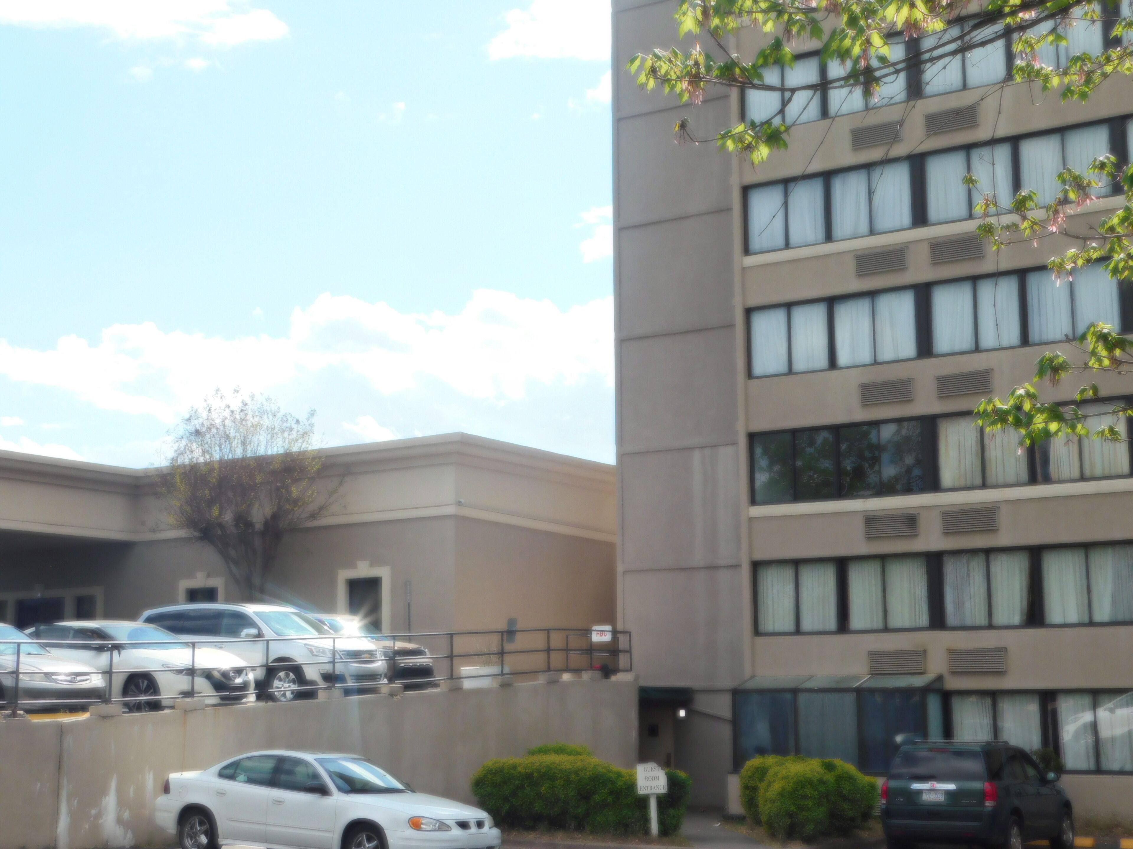 Edificio con varios espacios de estacionamiento y un letrero que indica la entrada para huéspedes.